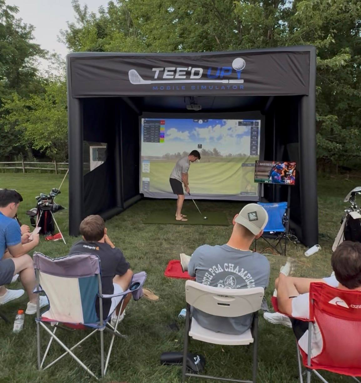 Guests watching a golfer take a shot inside the Tee’d Up simulator