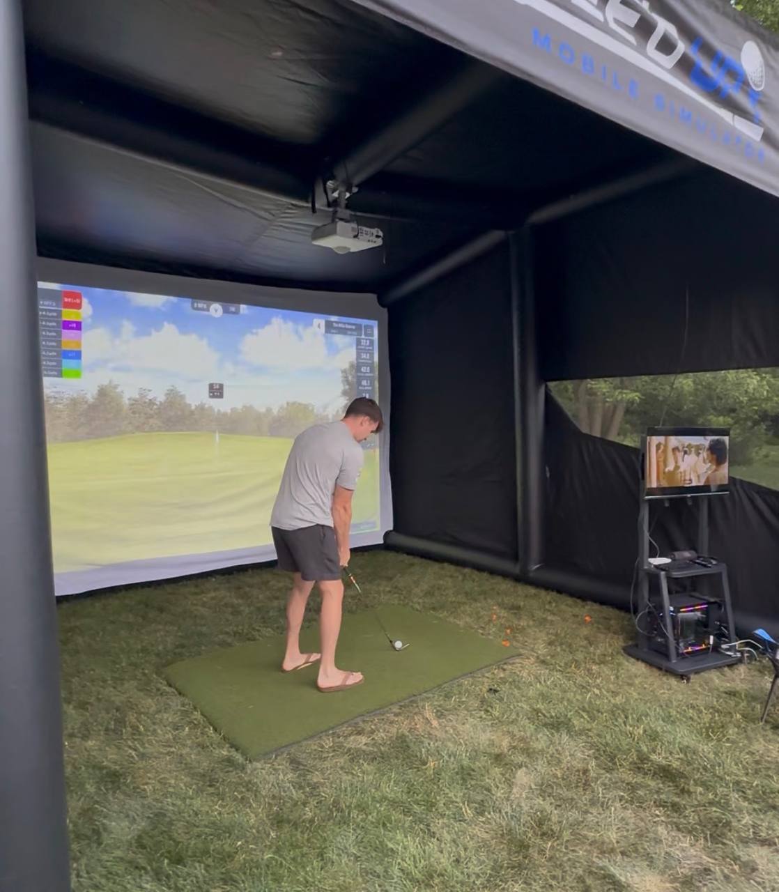 Interior shot of the Tee’d Up simulator showing the screen and launch setup